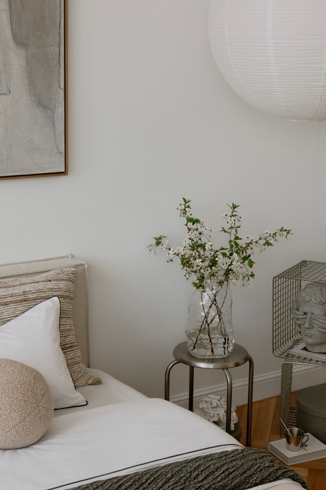 Décoration de chambre minimaliste au style épuré et zen Décoration de chambre minimaliste avec lit blanc, fleurs dans un vase en verre et sculpture artistique.