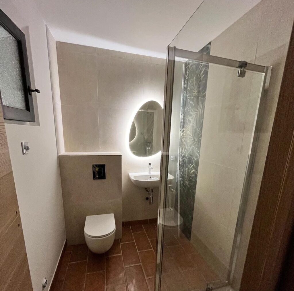Salle de bain design : WC suspendu et miroir rétroéclairé Salle de bain moderne avec WC suspendu, miroir rétroéclairé organique, vasque blanche et douche à l'italienne vitrée.